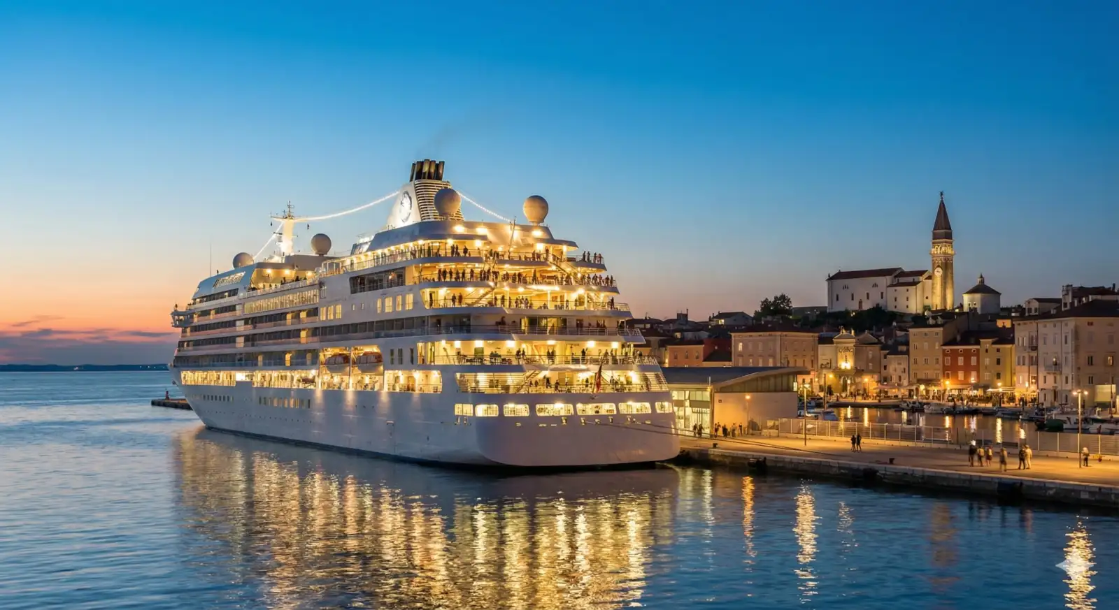 Luksuzni putnički kruzer usidren u luci, osvetljen toplim večernjim svetlima, simbolizujući uspeh kruzing turizma u Luci Koper.