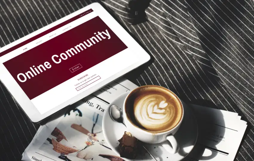 Tablet sa online community sadržajem, novine i kafa na stolu